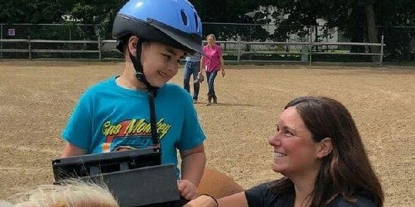 Therapist smiles at a client during a speech therapy session incorporating hippotherapy.