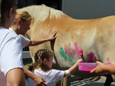 Child painting a horse during a speech therapy session.