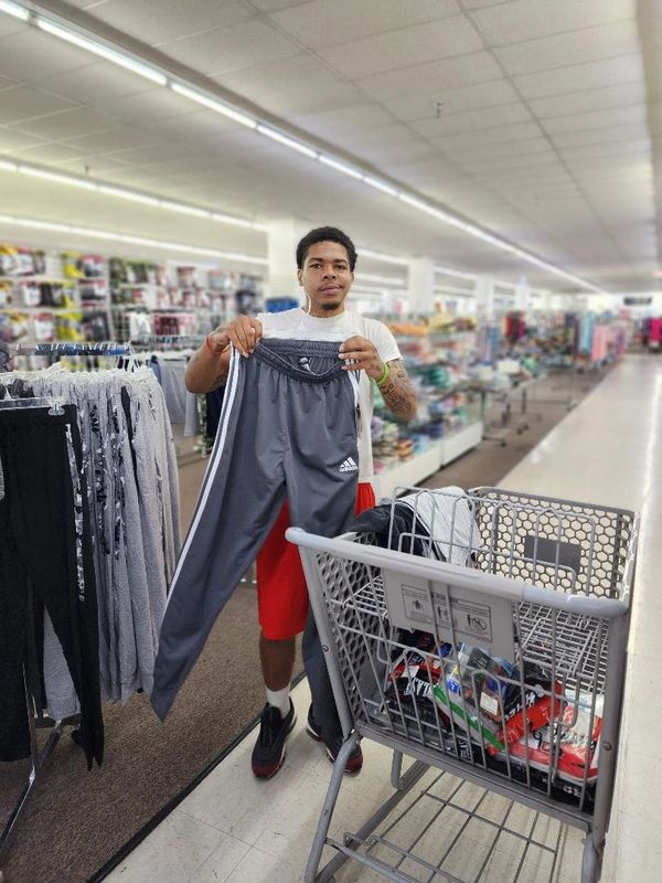 A CLIENT HOLDS UP HIS PANTS WHILE HES SHOPPING