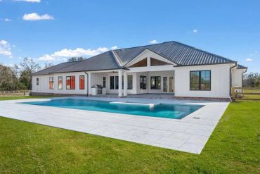 Modern house with a backyard pool and patio.