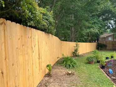 New wooden fence in a backyard with greenery.