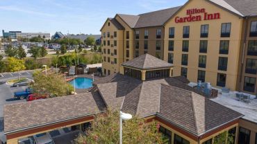 Exterior view of Hilton Garden Inn with pool and parking lot.