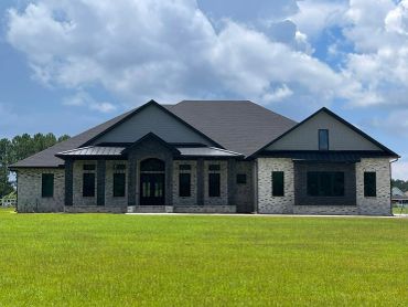 Large modern brick house with dark roof and windows.