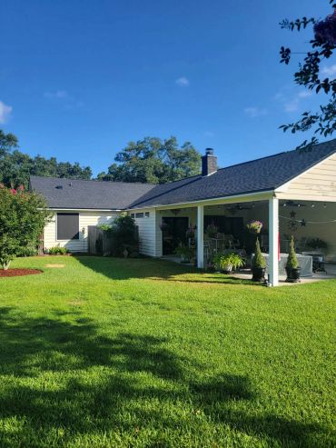 Spacious backyard with covered patio and green lawn.