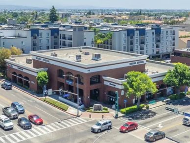 Busy urban intersection with a mix of commercial and residential buildings under clear skies.