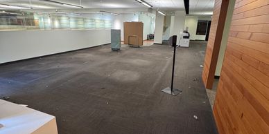 An empty office space with carpet flooring and some equipment scattered around.