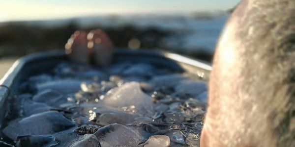 Man relaxing with feet up on an ice-filled cooler by the water.