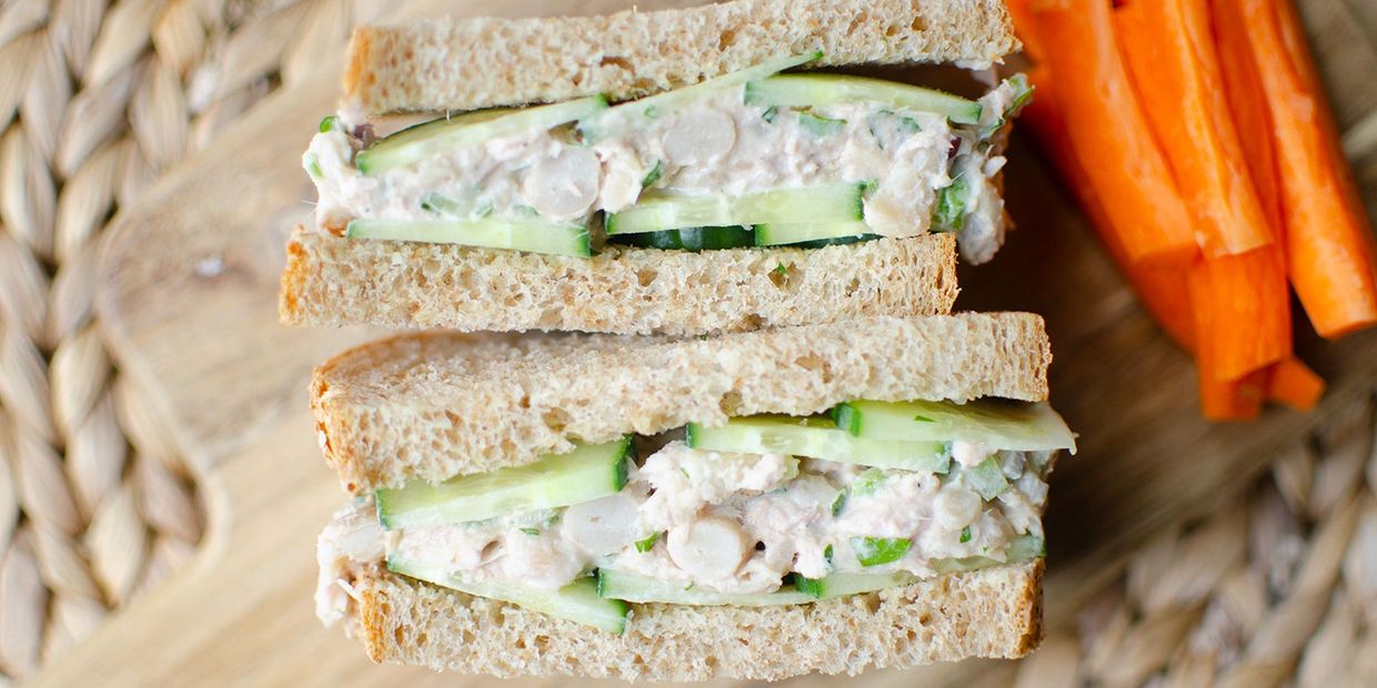 Close-up of a chicken salad sandwich with cucumber on whole wheat bread.