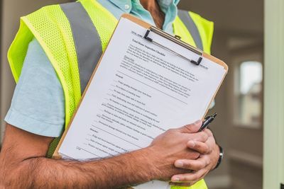 Construction worker holding a clipboard with a safety inspection checklist.