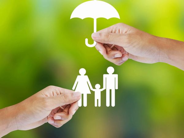 Hands holding paper cutouts of a family and umbrella symbolizing protection.