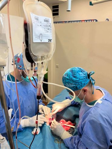 Surgeons perform operation with blood transfusion in progress.