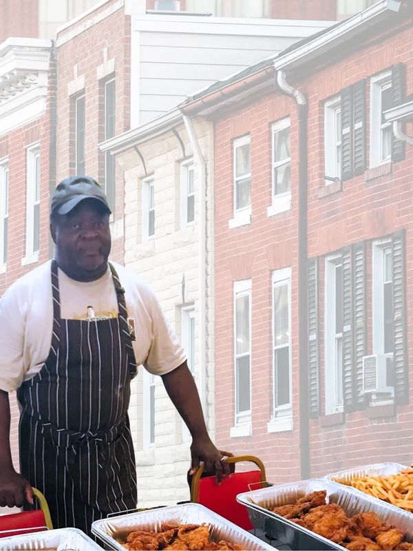 Man in apron serving fried chicken and fries outdoors.