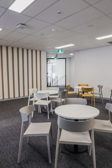 Breakout chairs and tables with feature timber slat wall behind.