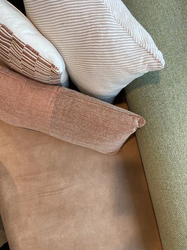 Booth seats with tan vinyl, textured green fabric, rusty orange and cream corduroy cushions.