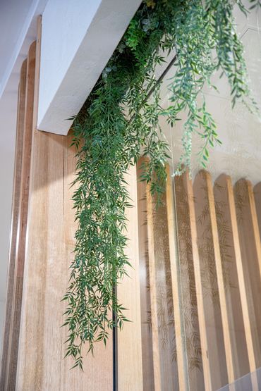 Shopfront detail with timber battles, rendered white wall and greenery.