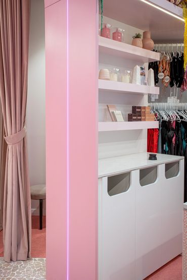Velvet pink curtains, pink tiled flooring, feature shelving, LED strip lights.