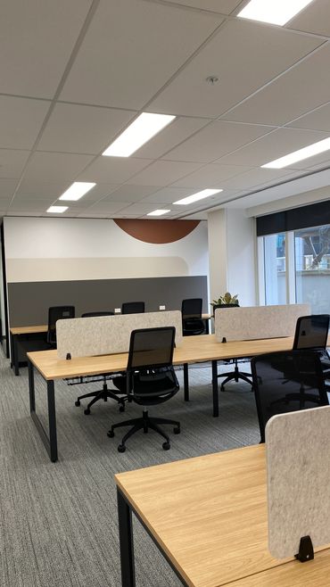 Open plan workstations with timber tops, black powdercoat bases and acoustic screens.