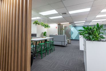 High breakout table in office setting, feature timber battens, storage and feature wall.