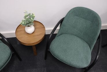 Green lounge chair and coffee table with plant on, in waiting area.