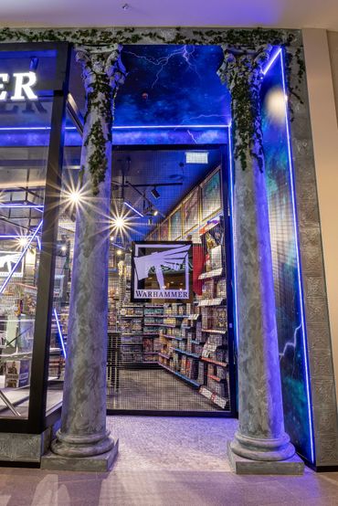 Shopfront design with faux columns representing realm gates, illuminated signage and crazy paving.