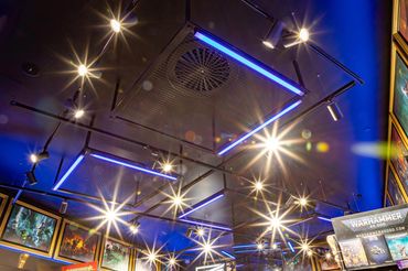 Retail feature black ceiling with black perforated metal panels, track lighting and blue tube light