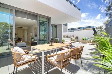 Residential patio setting with outdoor table and chairs and greenery.