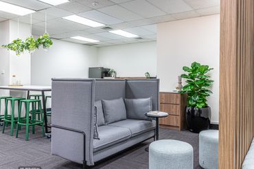 Collaboration zone within office Fitout showcasing high back lounge chairs and ottomans.