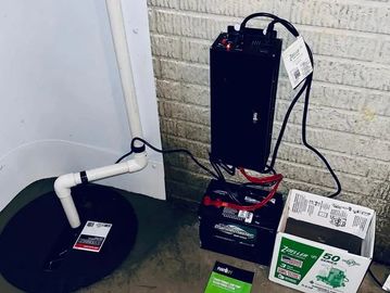 Battery backup system setup with pump and accessories on a floor.