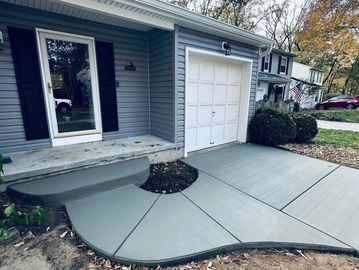 Newly poured smooth concrete driveway and porch steps at a suburban home.