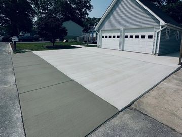 Freshly paved concrete driveway and sidewalk leading to a two-car garage.