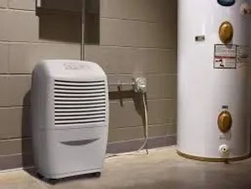 A dehumidifier operating next to a water heater in a basement.