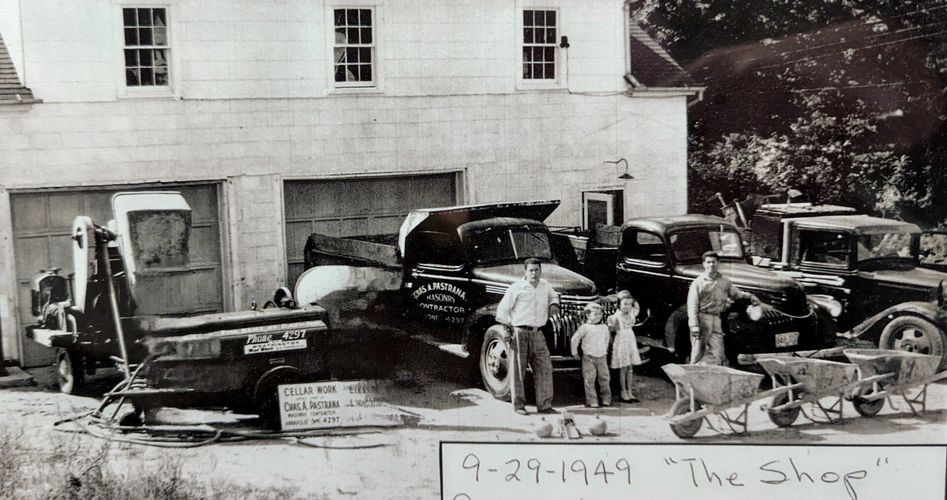 1949 photo of a masonry contractor's shop with trucks and workers.