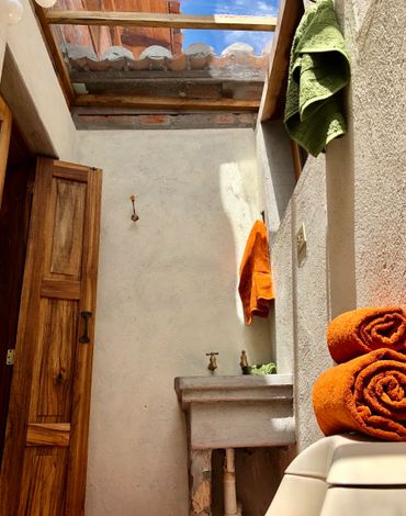 Rustic bathroom with natural light from a skylight and colorful towels.
