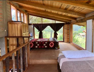 Cozy rustic bedroom with large windows and wooden interior.