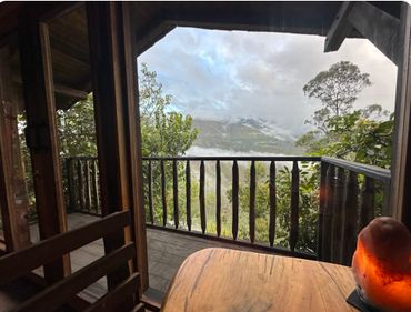 View from a wooden cabin balcony overlooking foggy mountains and trees.