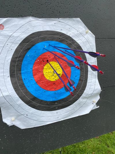 Four arrows clustered close to the bullseye on an archery target.
