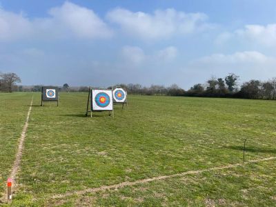 Archery targets set up in a grassy field under a partly cloudy sky.