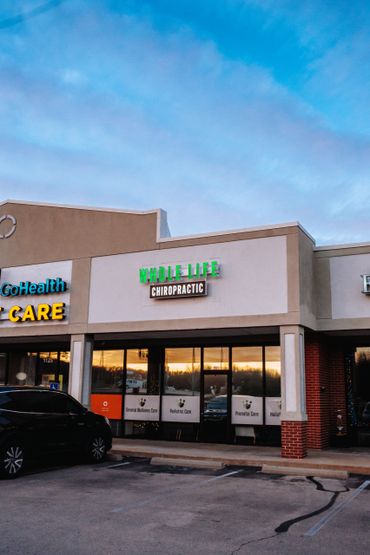 Whole Life Chiropractic clinic in a shopping center at sunset.