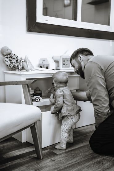 Father and toddler playing together by a toy shelf in a cozy room.