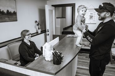 A man holds a cheerful baby on a counter while a woman smiles at them.