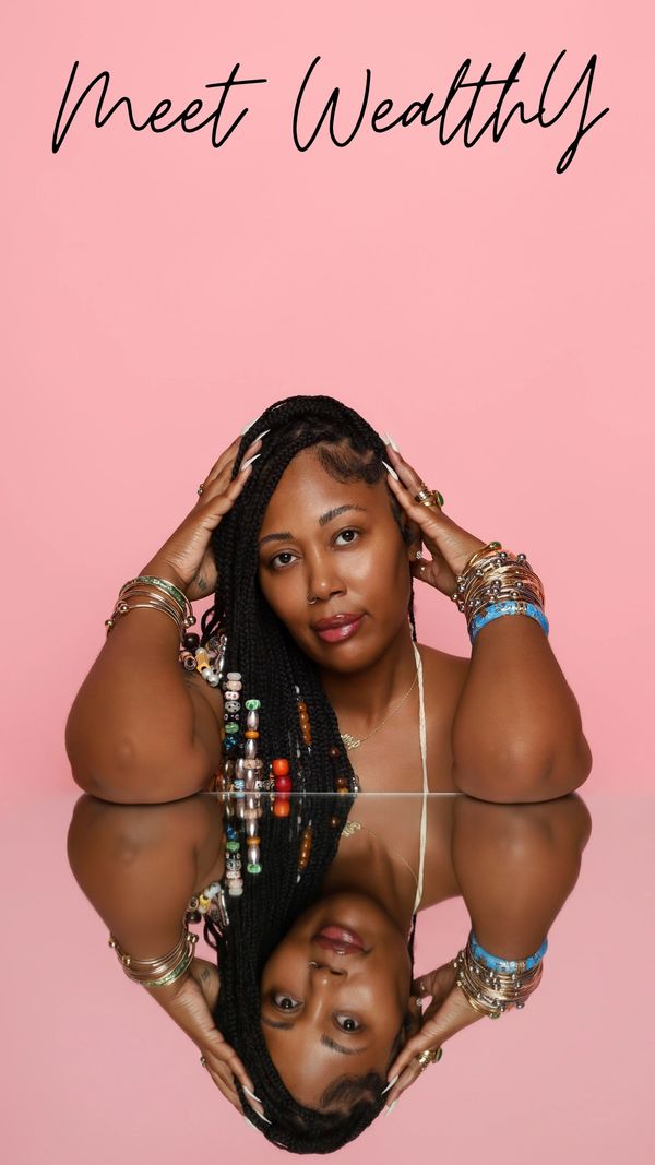 Woman with braided hair and jewelry against pink background.