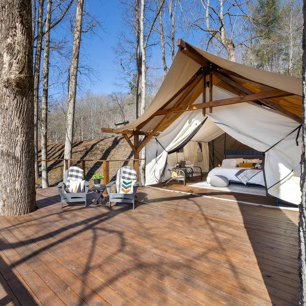 Cozy outdoor glamping setup with lounge chairs and tent.