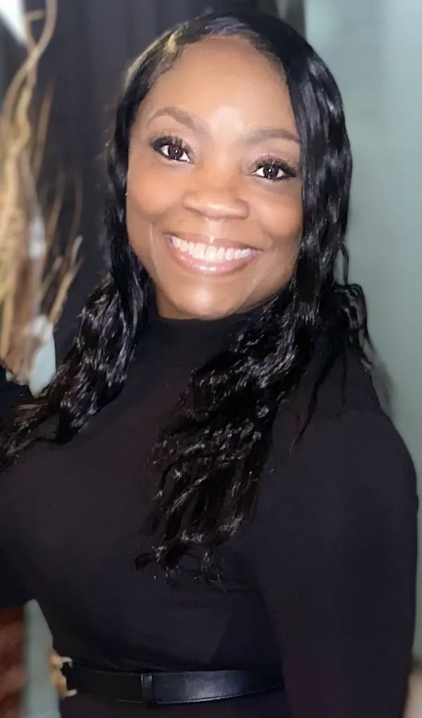 Smiling woman in black attire with long hair.