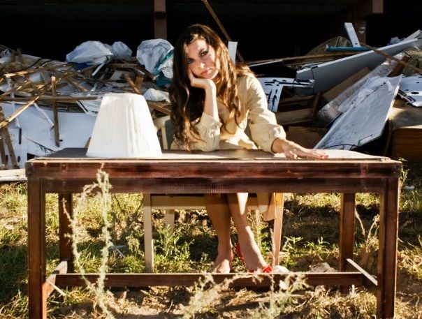 young woman dressed up, sitting at an empty desk in the middle of a construction site