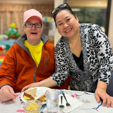 Staff member & elder smile together for a picture while at Gentog Senior Daycare in Tigard, Oregon