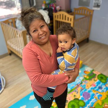 A staff member and baby smile together for a picture while at Gentog Daycare in Tigard, Oregon