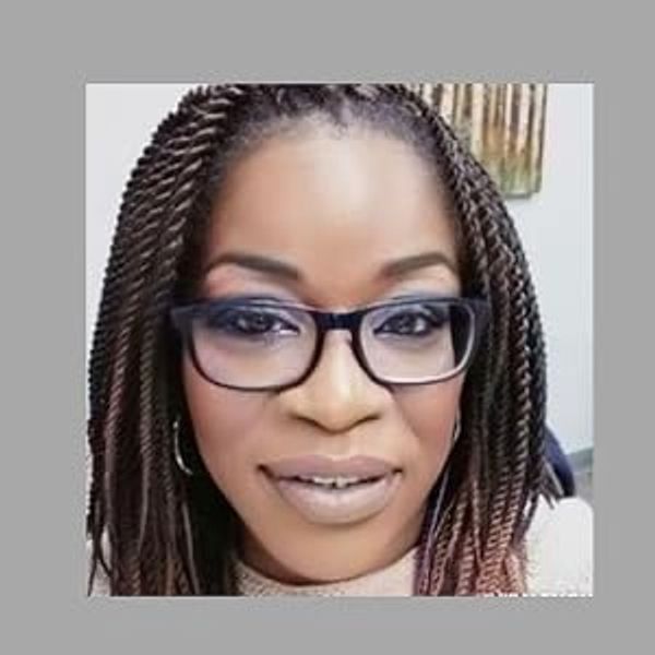 Woman with braided hair and glasses smiling.