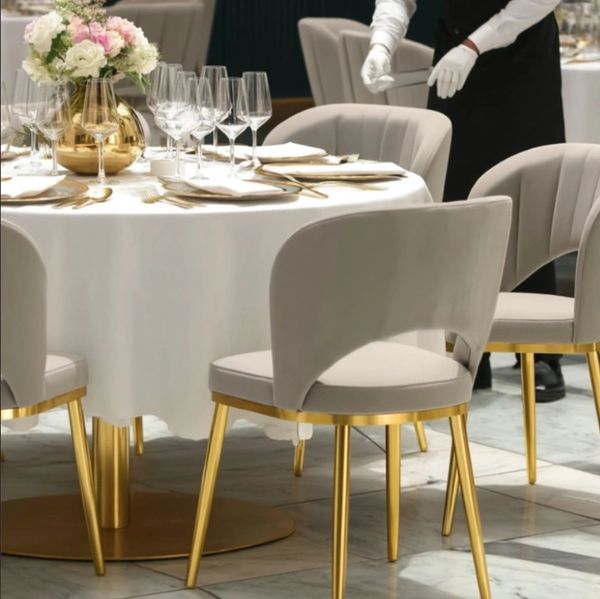 Elegant dining setup with gold-accented chairs and a flower centerpiece.