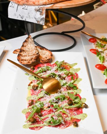 Beef carpaccio with capers, arugula, shaved parmesan, and grilled crostini at Mangia E Bevi