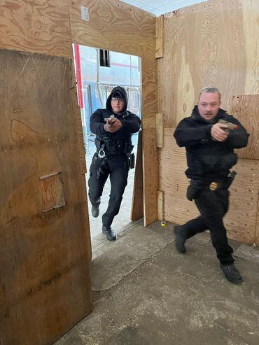 Two security patrol officers conducting a tactical training drill indoors.